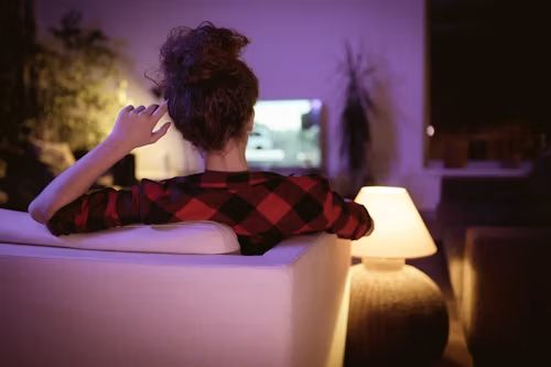 Viewer relaxing on the couch watching TV at night